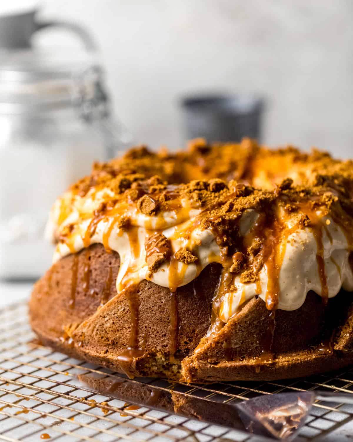 biscoff pound cake on a wire rack with glaze, caramel, and crushed cookies on top. 