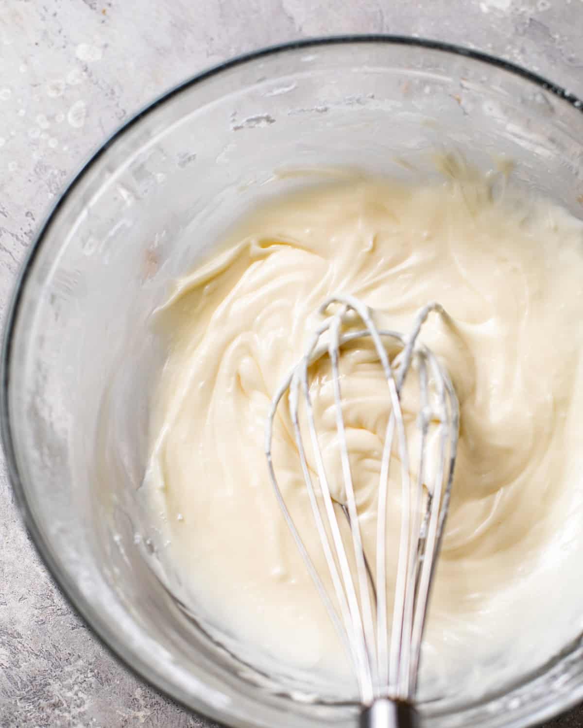 almond glaze mixed together in a mixing bowl with a whisk.