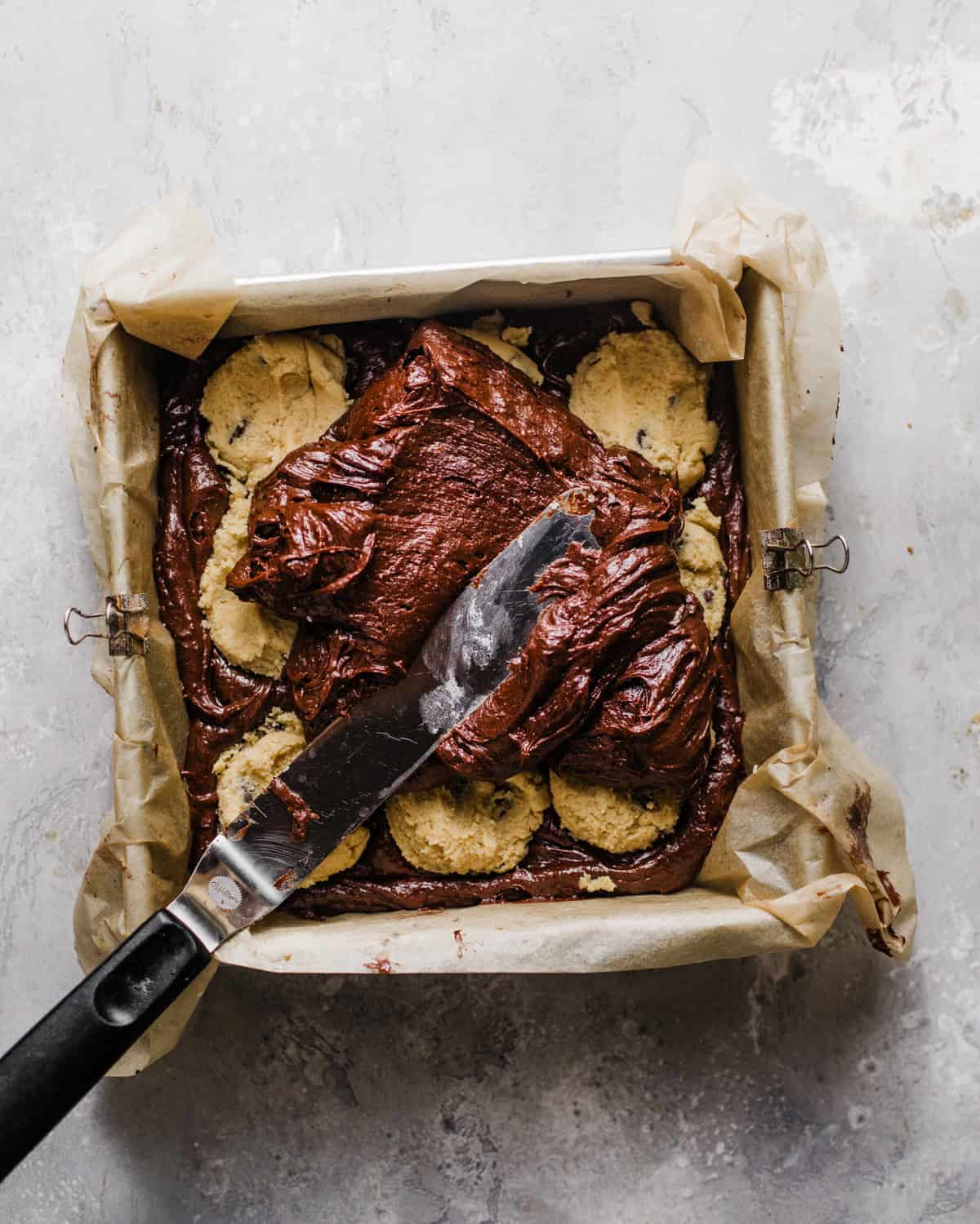 half of the brownie batter in the baking pan with cookie dough batter on top.