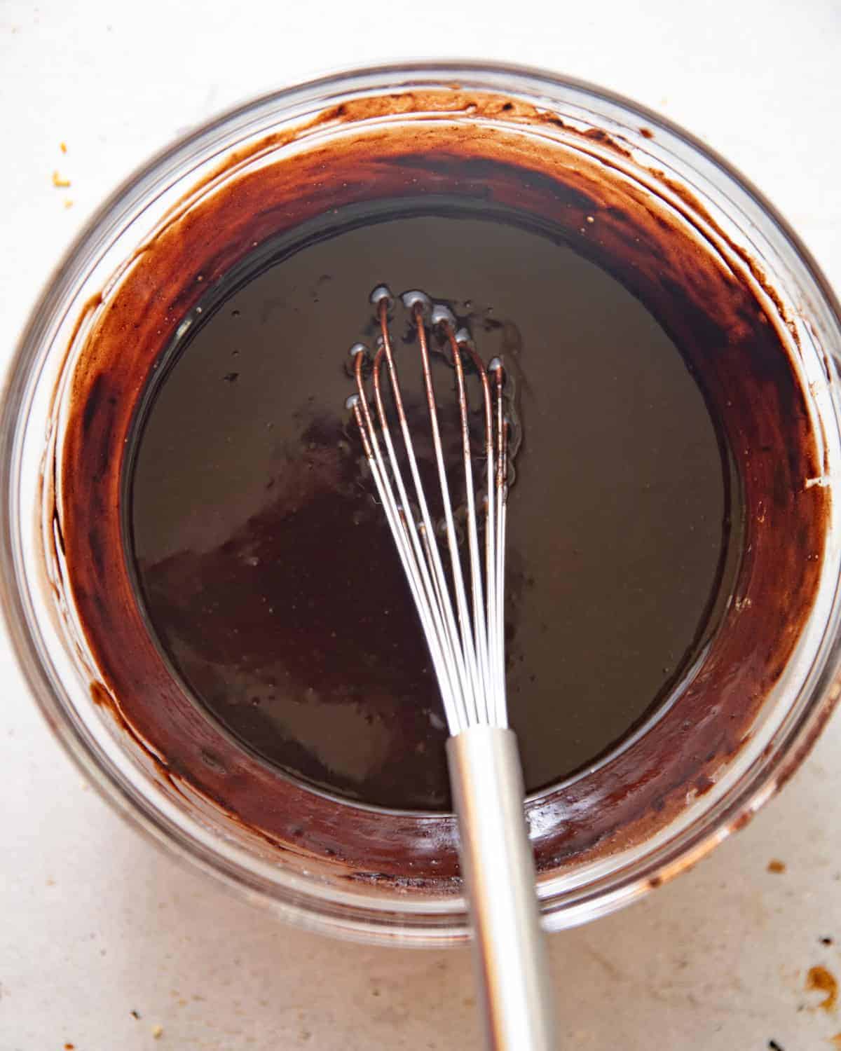 melted chocolate, butter, oil, espresso powder, and cocoa powder mixed together in a bowl. 