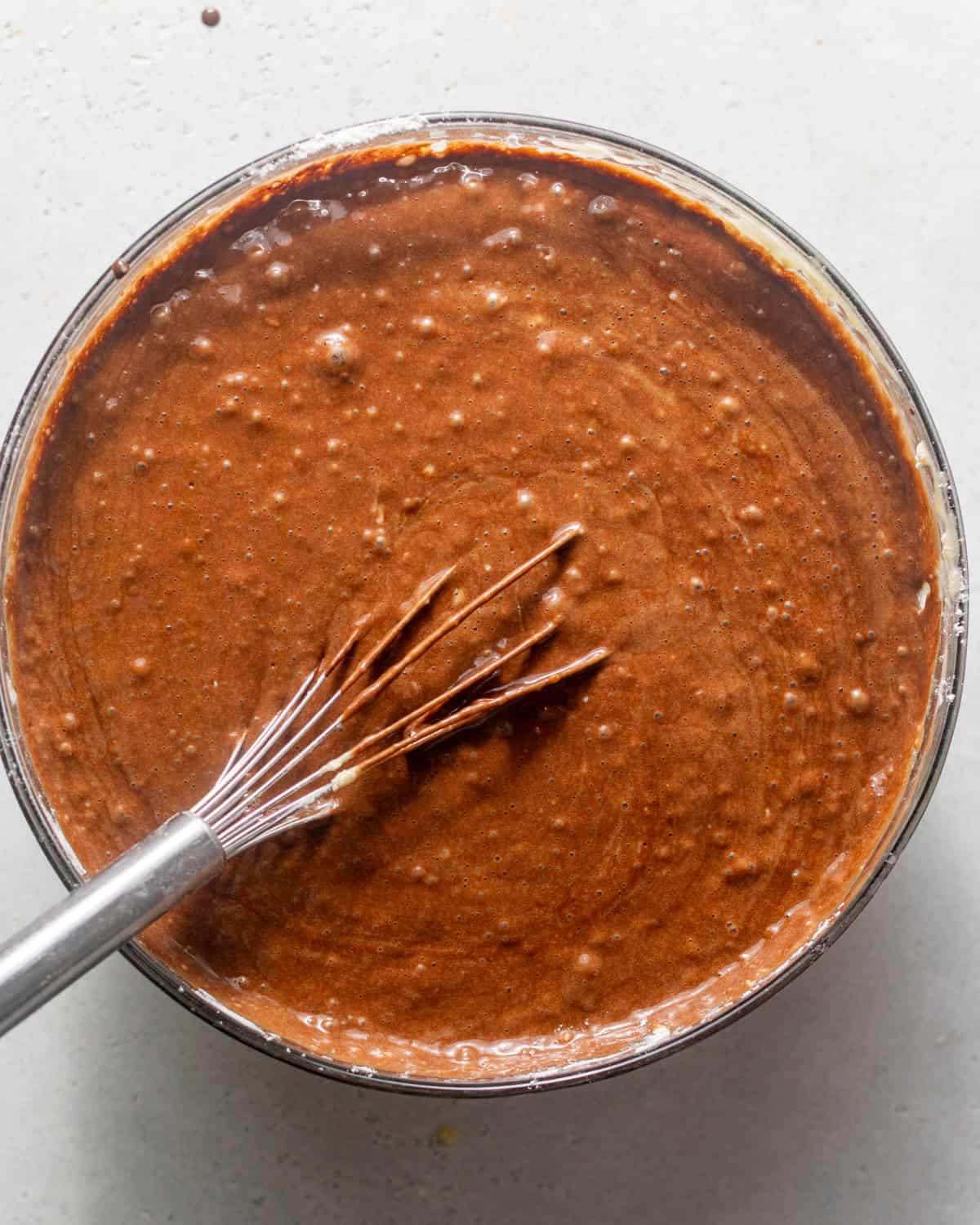 chocolate mud cake batter in a mixing bowl with a whisk. 