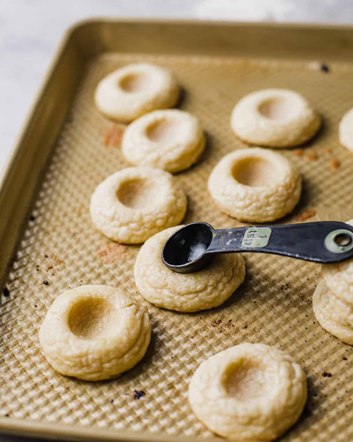 the back of a spoon pressing the thumbprint into the cookies.