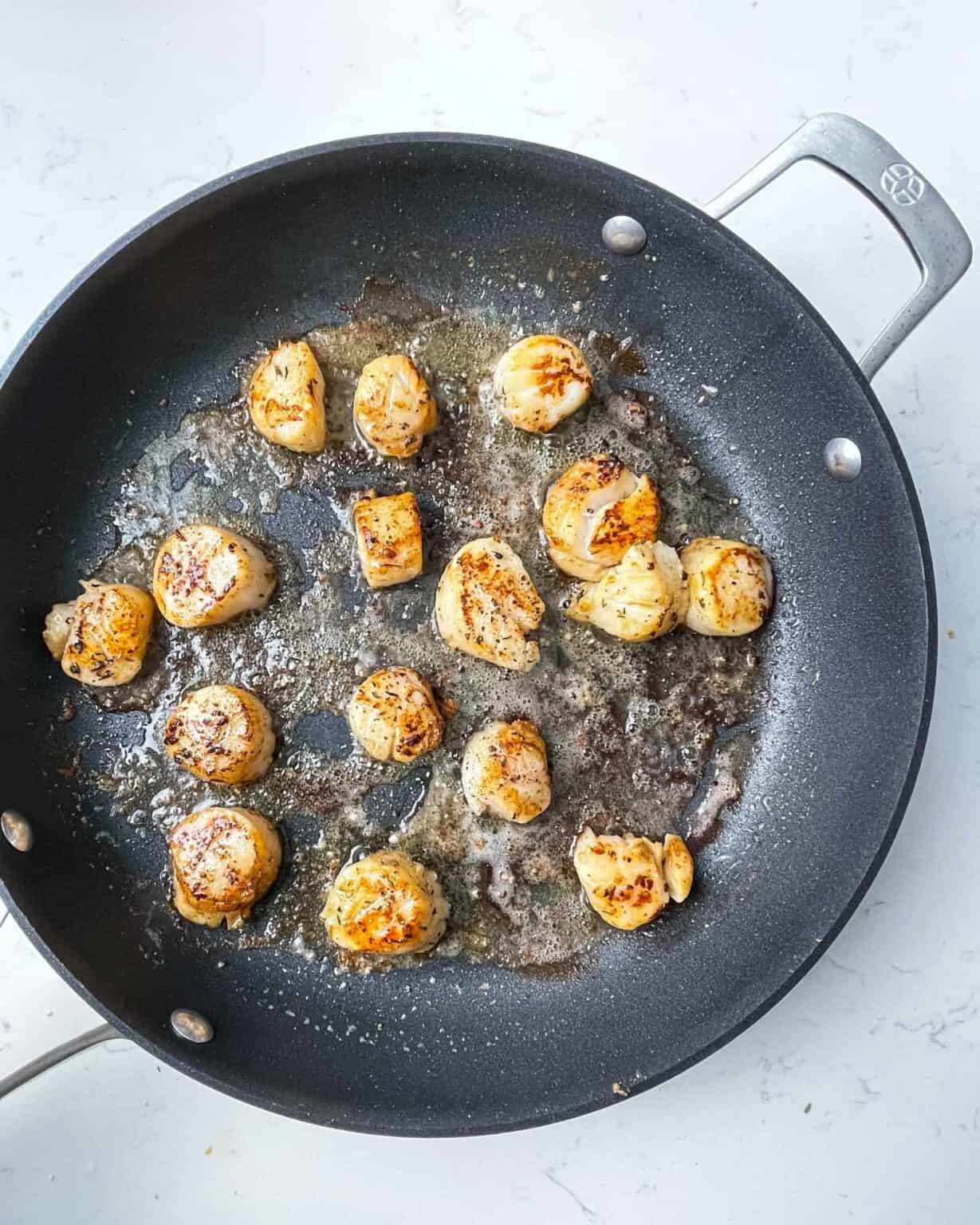 seared scallops in a skillet.