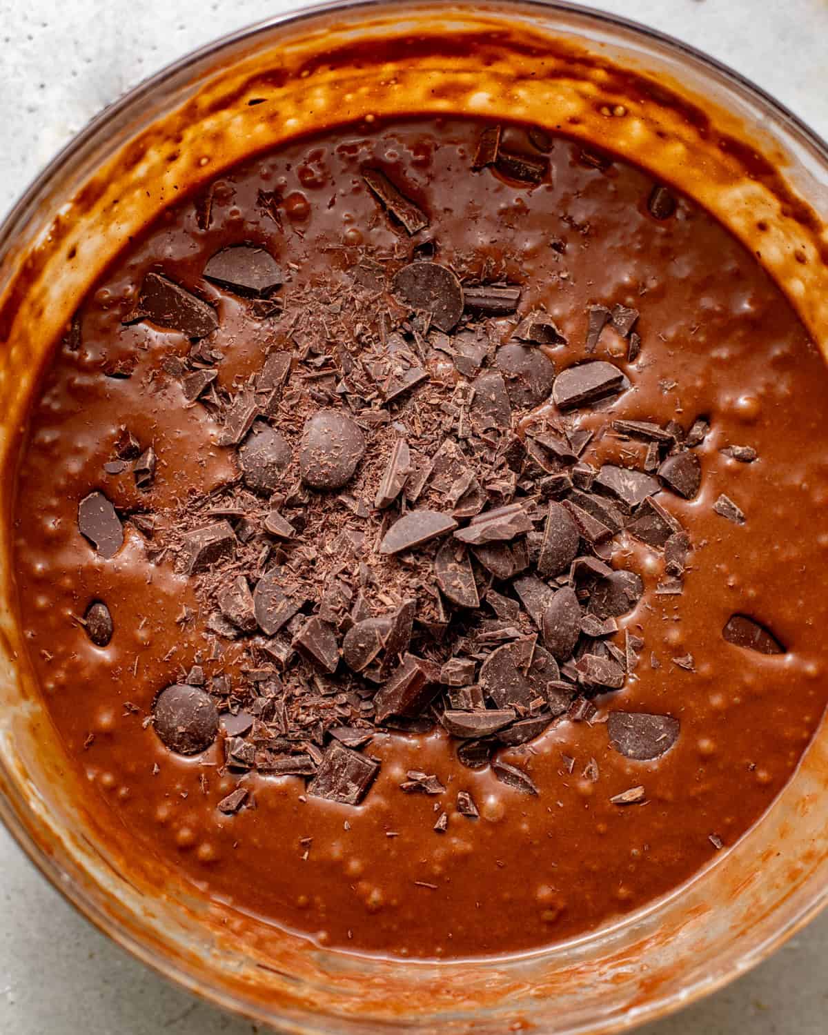 chocolate cake batter in a bowl with chopped chocolate folded into the batter.