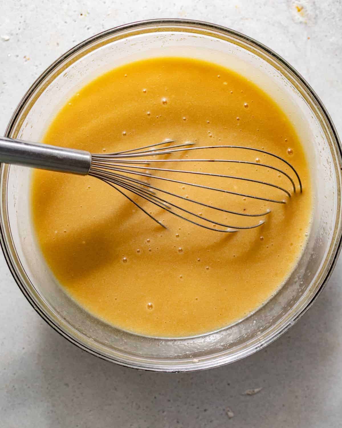 wet ingredients whisked together in a bowl - vegetable oil, melted butter, sugar, eggs, egg yolk, vanilla extract, and sour cream.