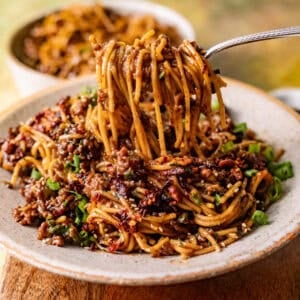 saucy mongolian ground beef noodles in a bowl with a fork pulling the noodles out of the bowl.