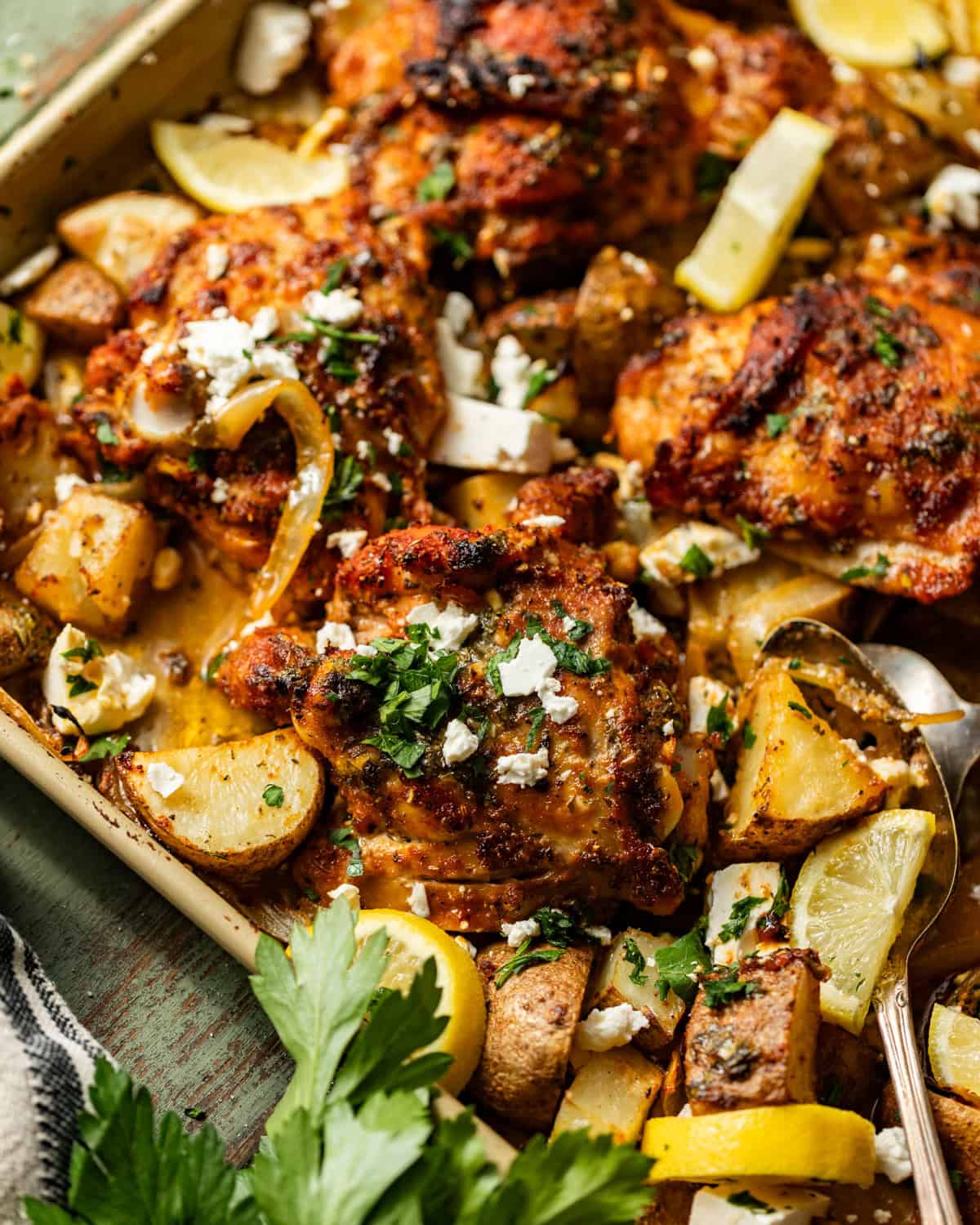 sheet pan chicken thighs and potatoes topped with parsley and feta.