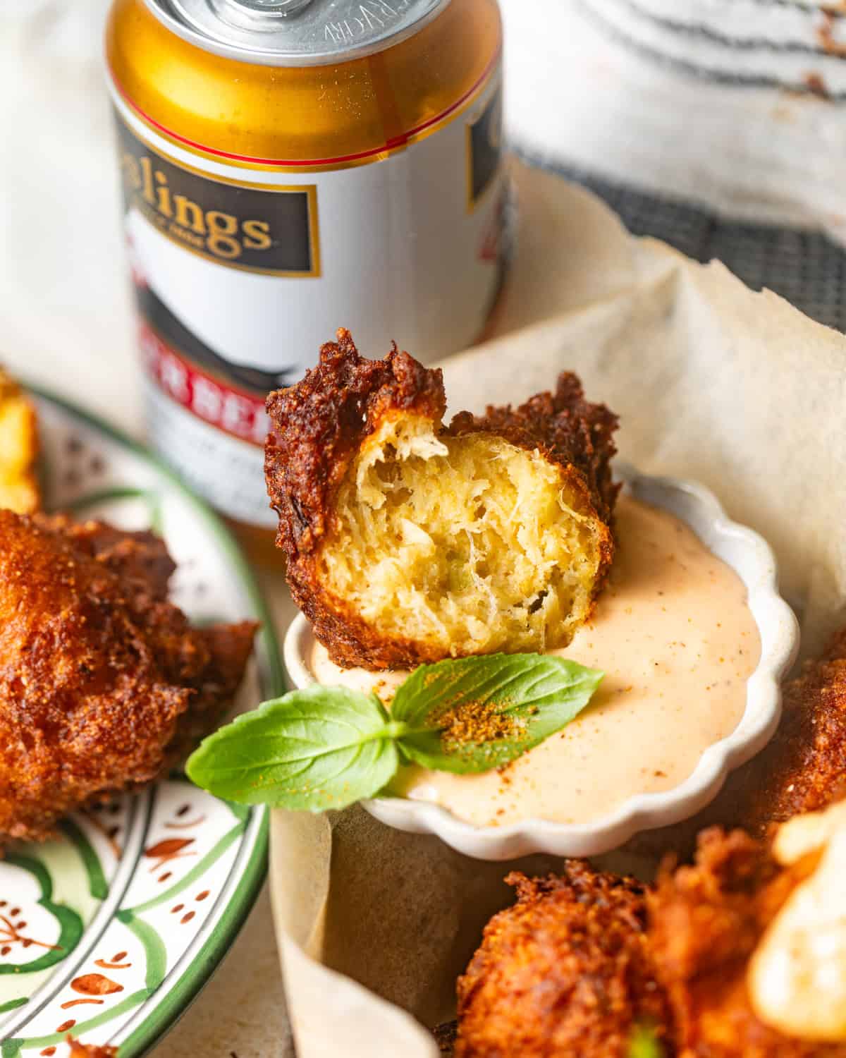 crab beignet cut in half and dipped into remoulade sauce.