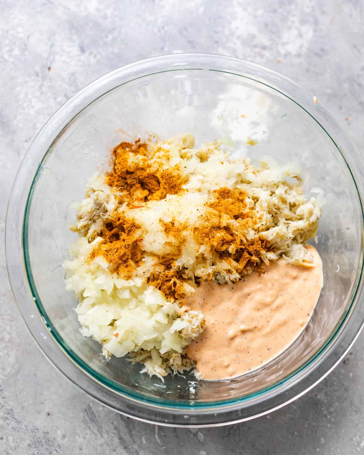 crab meat, seasonings, remoulade sauce, eggs, grated onion, and milk in a bowl.