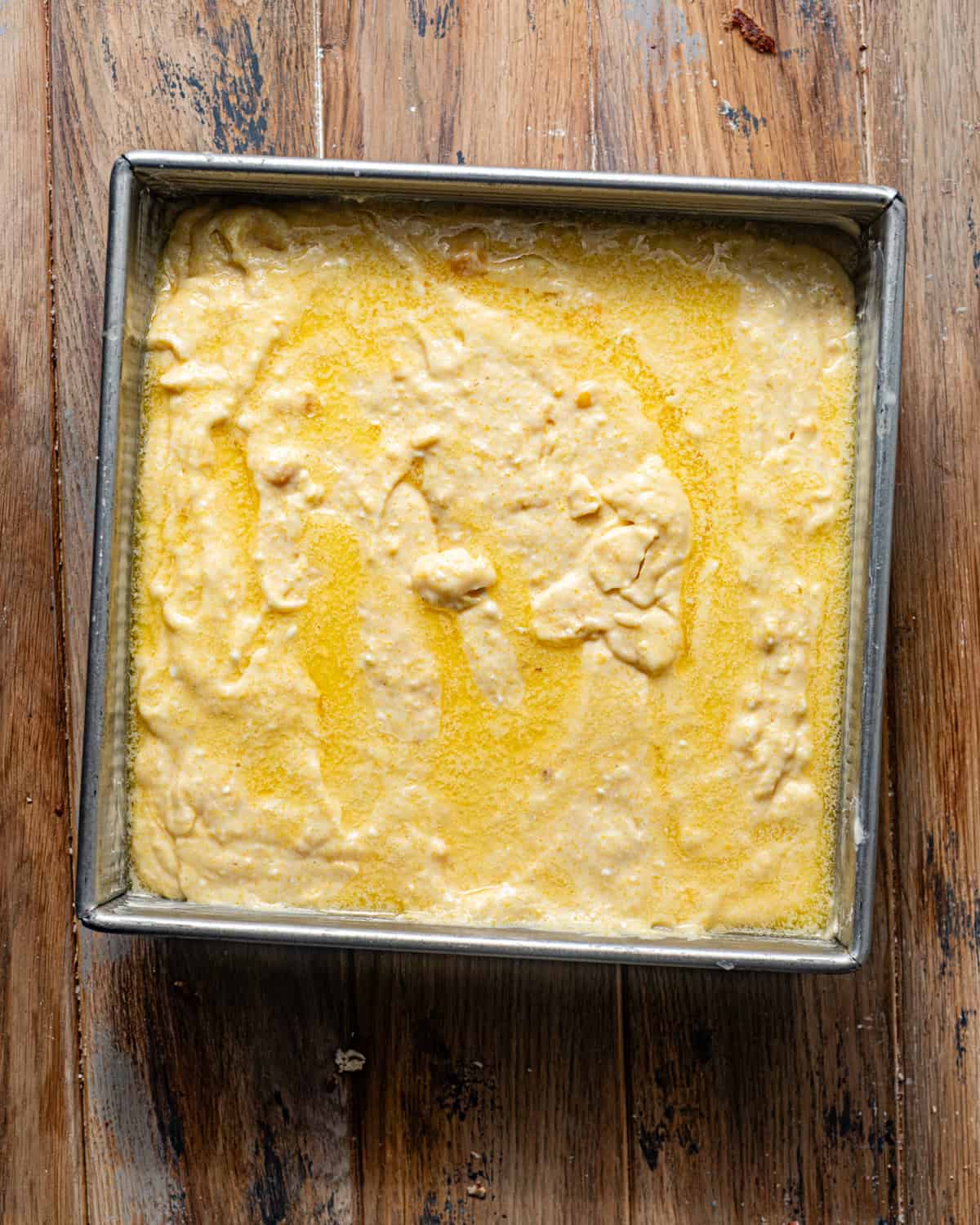 cornbread batter in a baking pan with melted butter poured on top. 