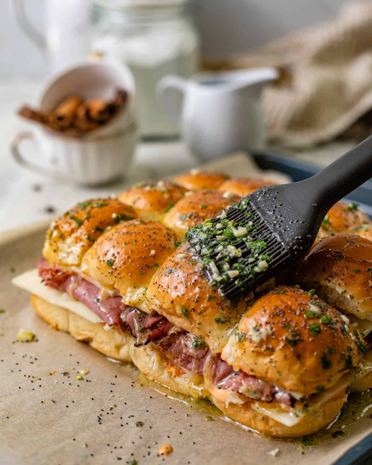 garlic butter with poppy seeds being brushed on top of the rolls. 
