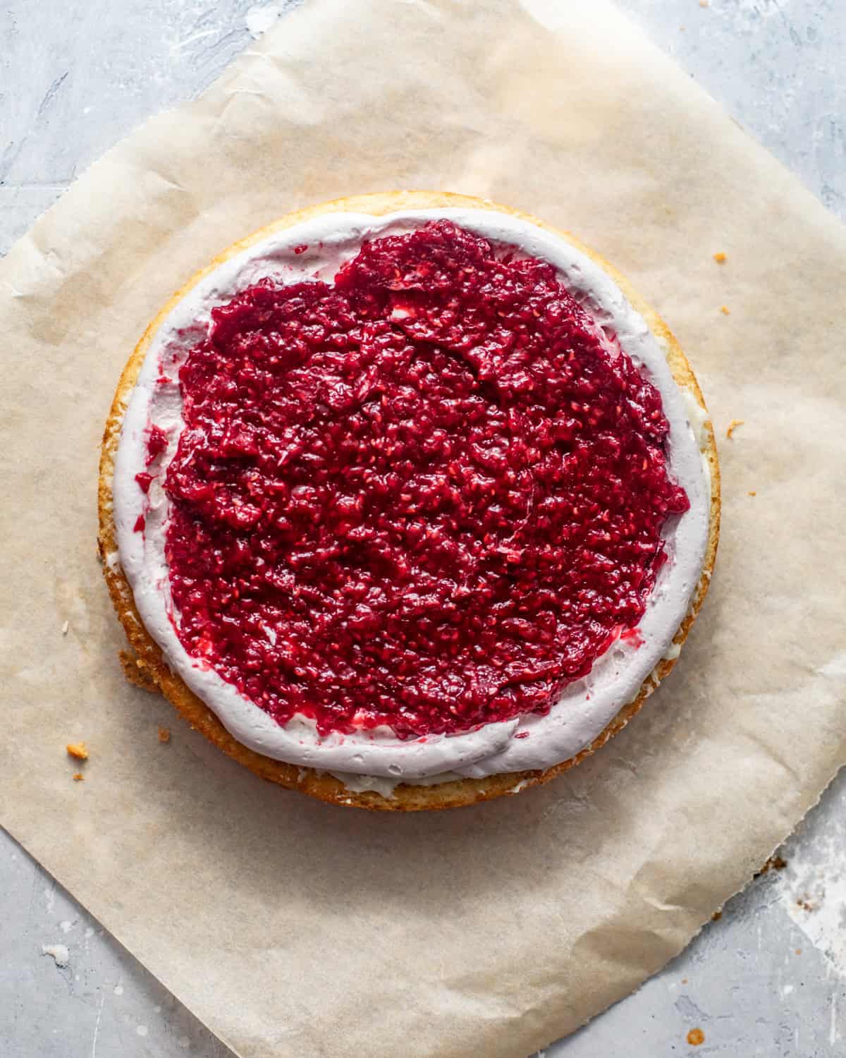 one cake layer with whipped white chocolate ganache and raspberry filling on top with a white chocolate buttercream border piped around the perimeter of the cake.