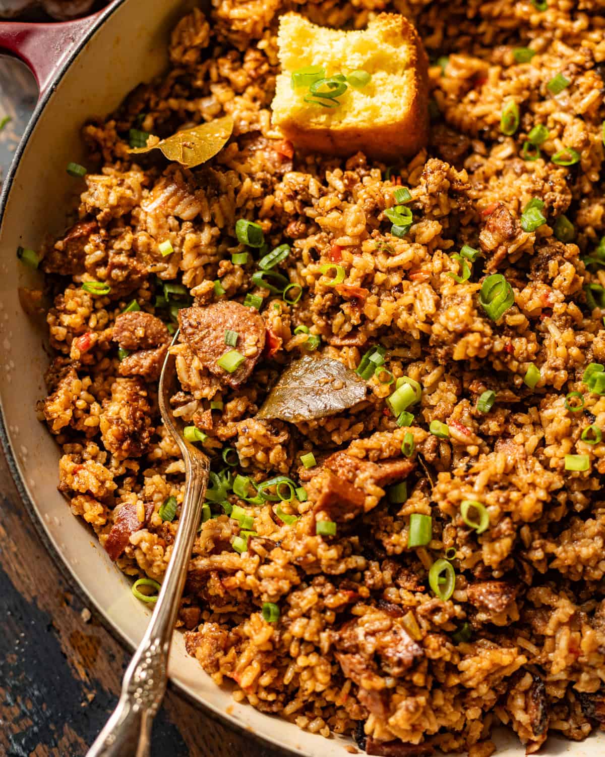 up close photo of louisiana dirty rice in a skillet with a serving spoon. 