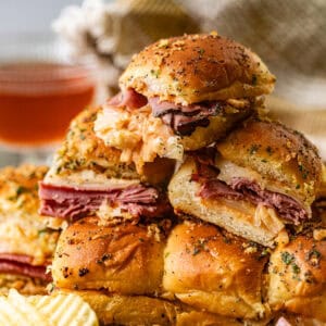 reuben sliders stacked on top of each other with chips on the side.