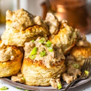 southern biscuits and gravy on a plate garnished with chopped green onions.