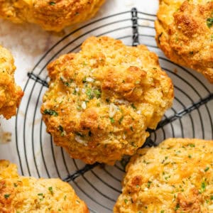 cheddar bay biscuits on a wire rack topped with garlic butter and flaky sea salt.