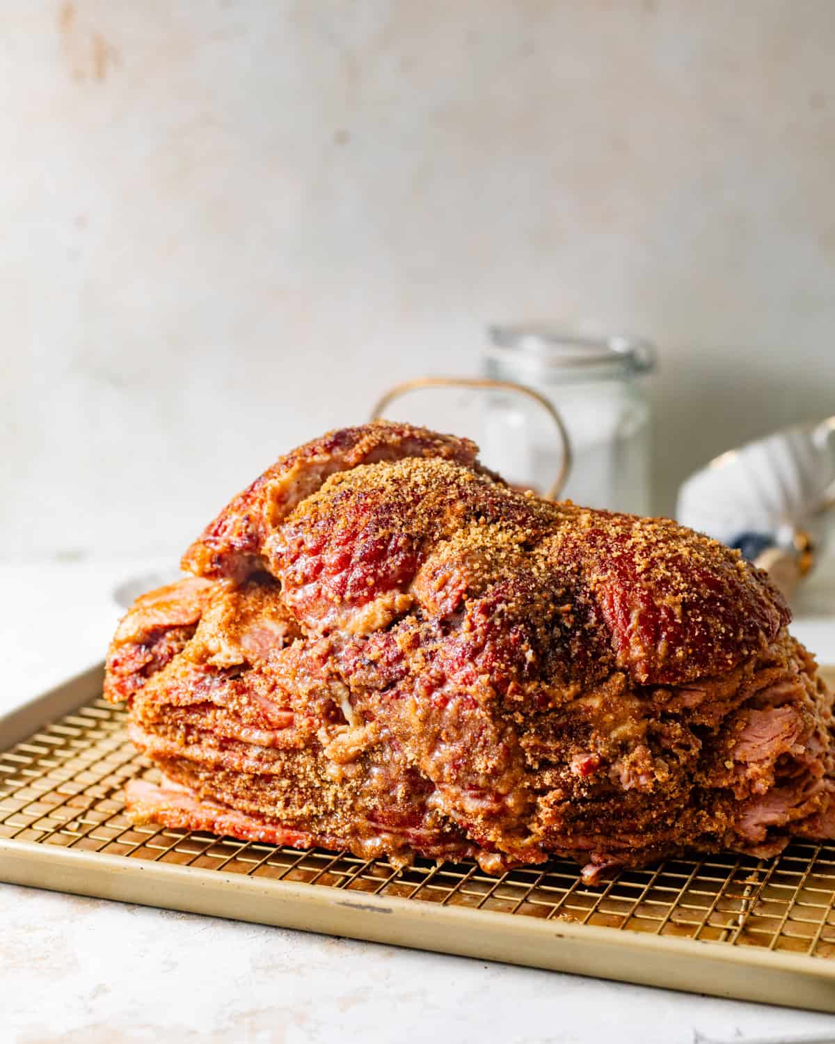 ham coated in honey dijon glaze and seasonings on a wire rack.