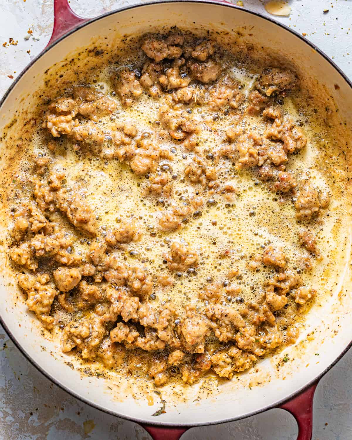 sausage, seasonings, and herbs cooked in a pot. 