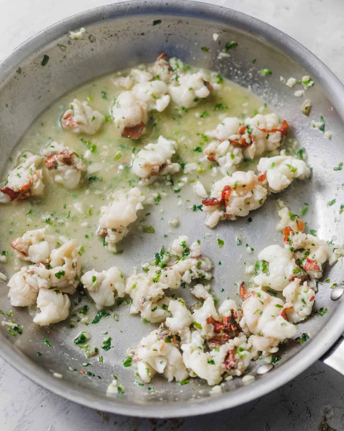 chunks of lobster in a pan cooked in garlic butter.