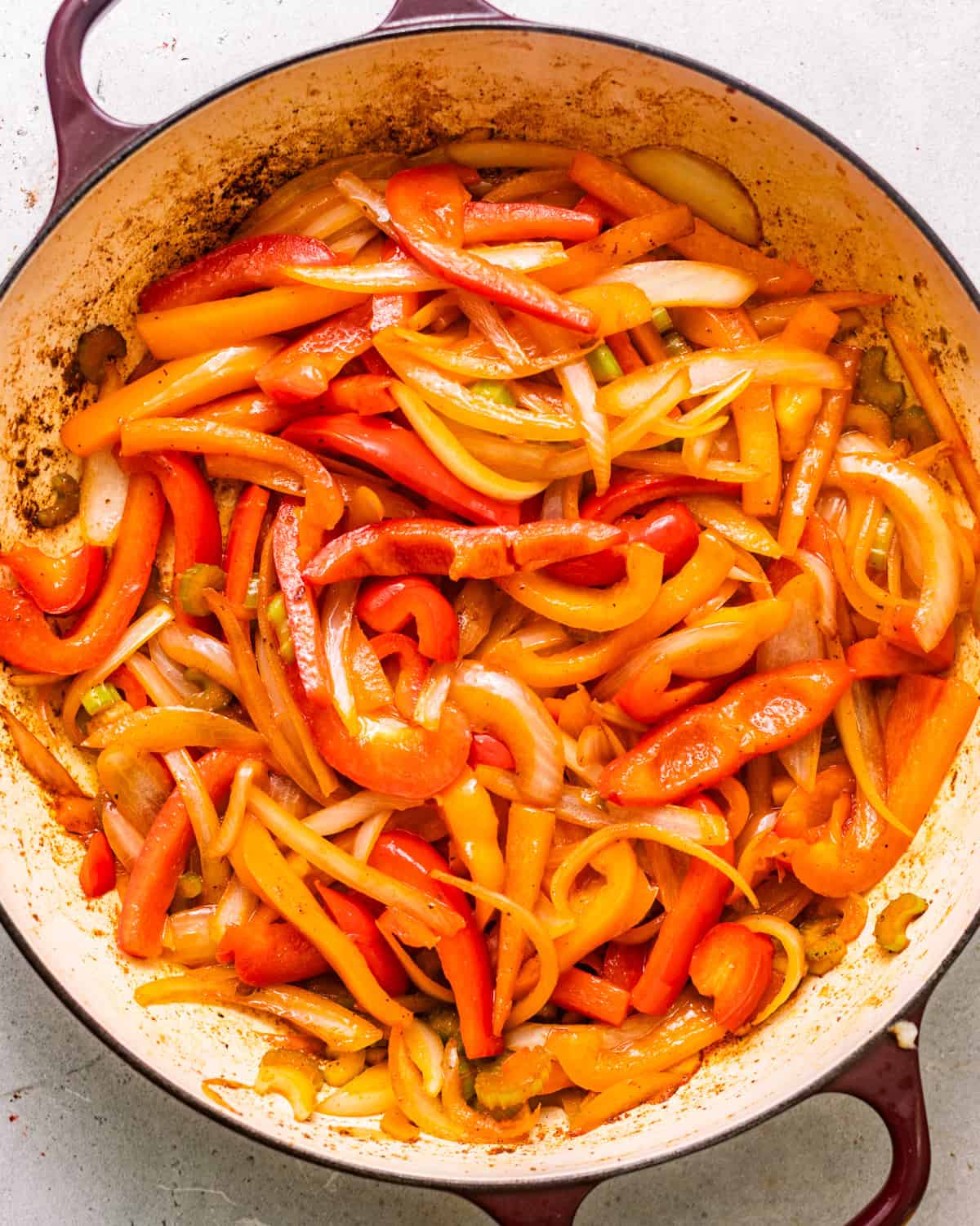 sauteed onions, bell peppers, celery, and garlic in a pot with seasonings.