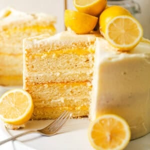 lemon layer cake on a cake stand cut to show the inner lemon curd filling.
