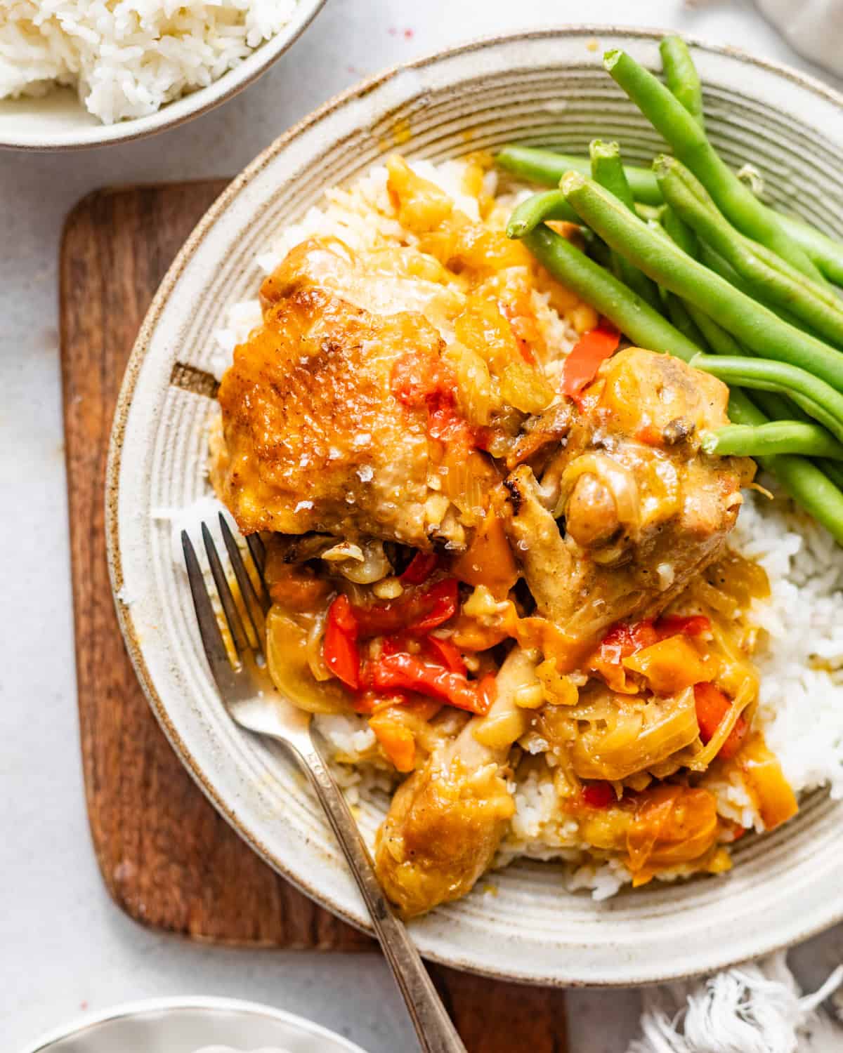 smothered chicken on plate with rice and green beans. 