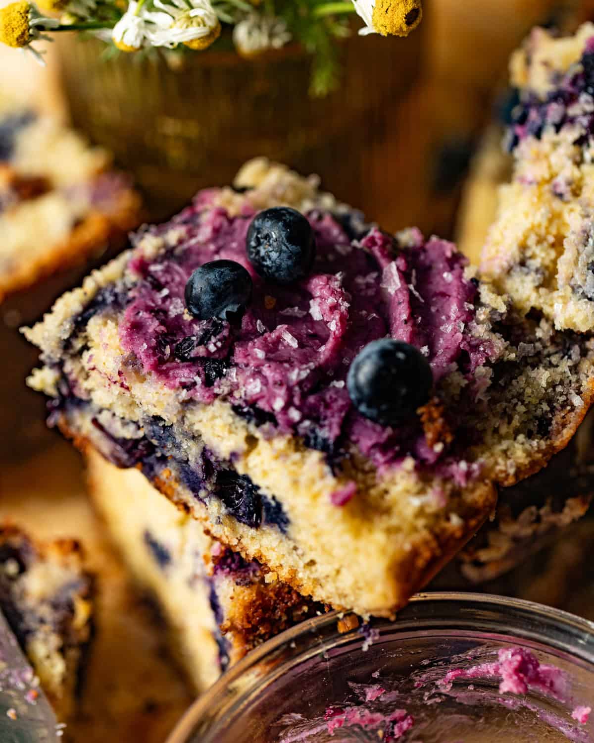 blueberry butter on top of a slice of blueberry cornbread with fresh blueberries and flakey salt on top. 