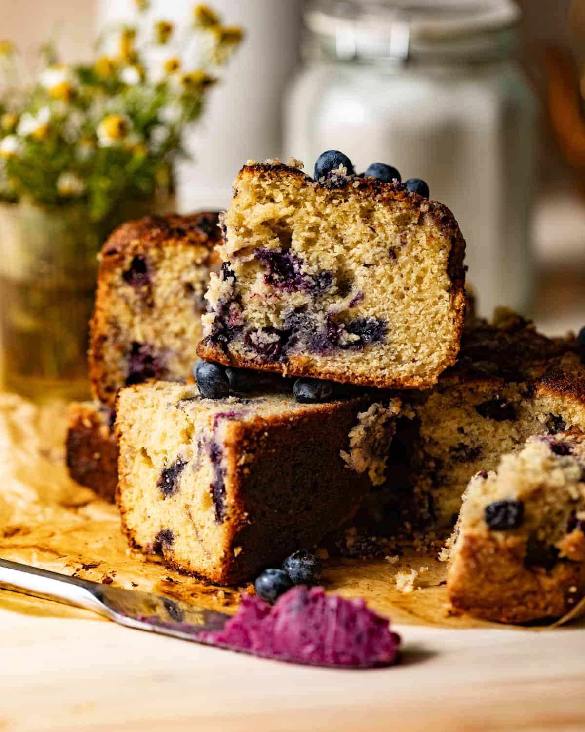 sliced blueberry cornbread stacked on top of each other with fresh blueberries on top. 