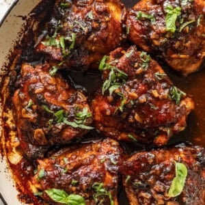 honey garlic chicken thighs in a skillet topped with a sticky honey garlic glaze and chopped parsley.