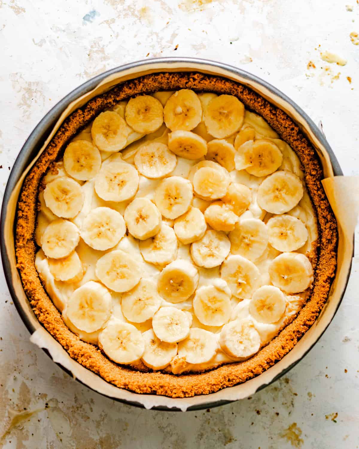 half of the cream filling in a springform pan with sliced bananas on top.