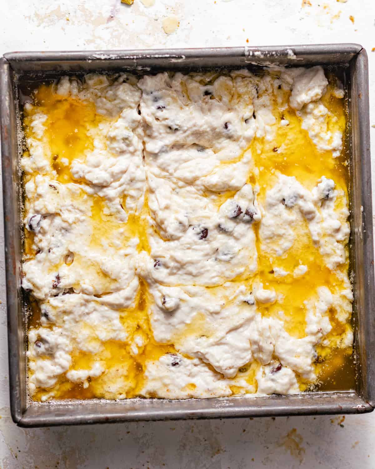 chocolate chip butter swim biscuit dough in a baking dish submerged in melted butter.