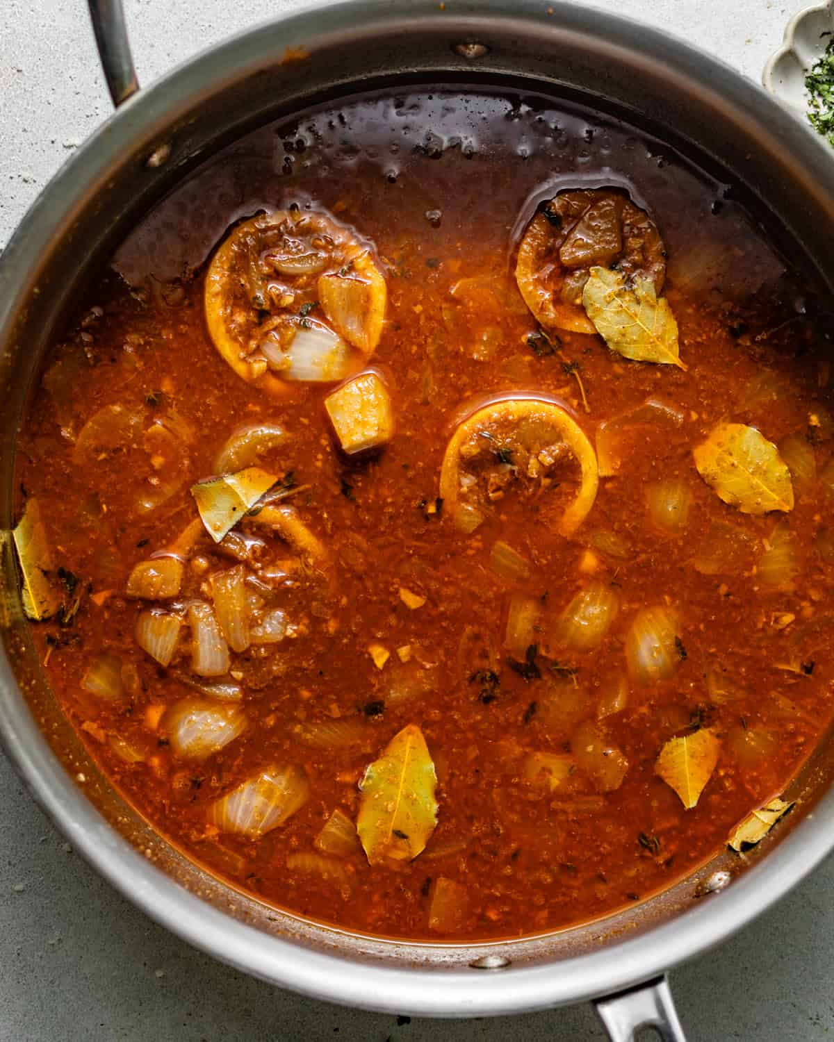 worcestershire garlic butter sauce in a pan with lemons, onions, and seasonings.