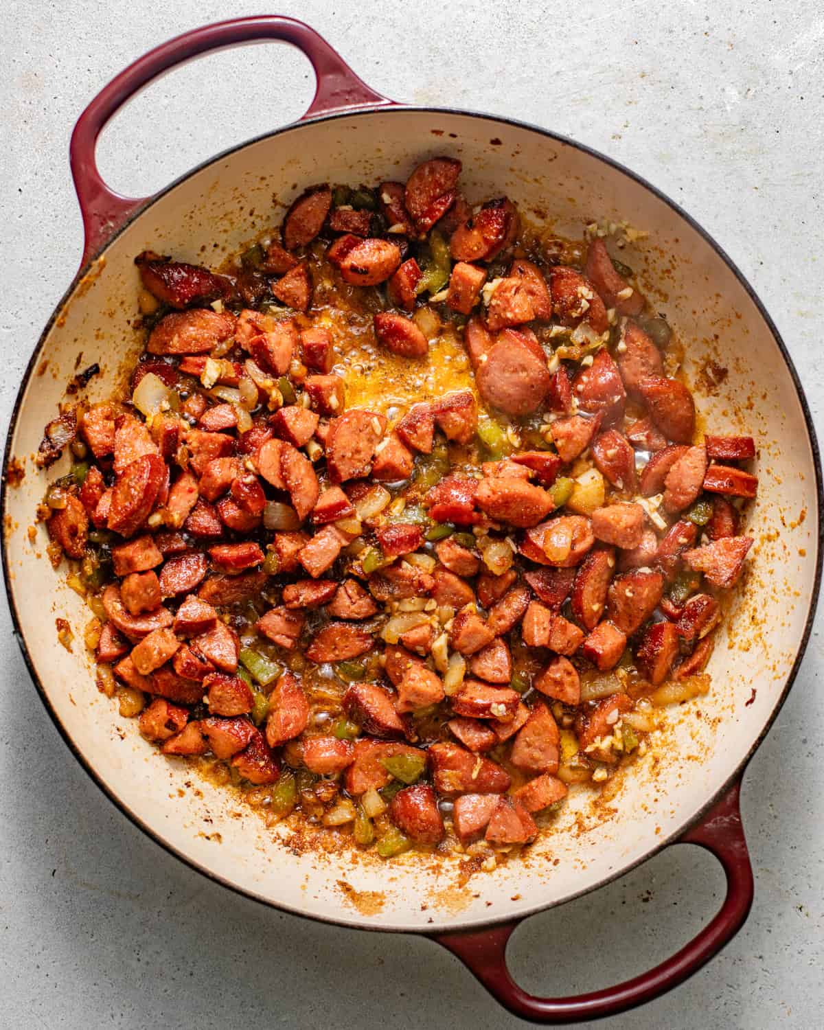 sausages, diced onion, and green bell pepper cooking in a large skillet until softened and slightly browned.