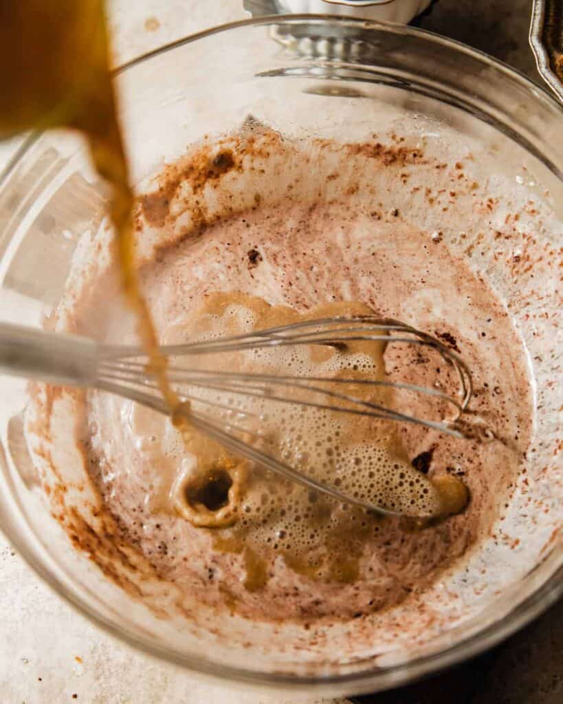 hot coffee being poured into the chocolate cake batter.