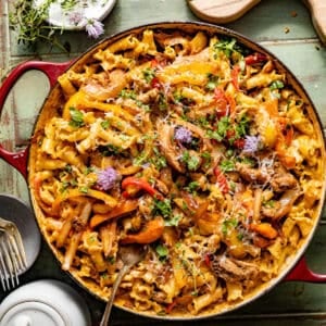 rasta pasta in a large skillet topped with cilantro, sauteed bell peppers, and jerk chicken.