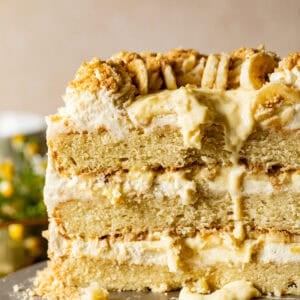 banana pudding cake on a cake stand with the cake cut open to see the inside layers.