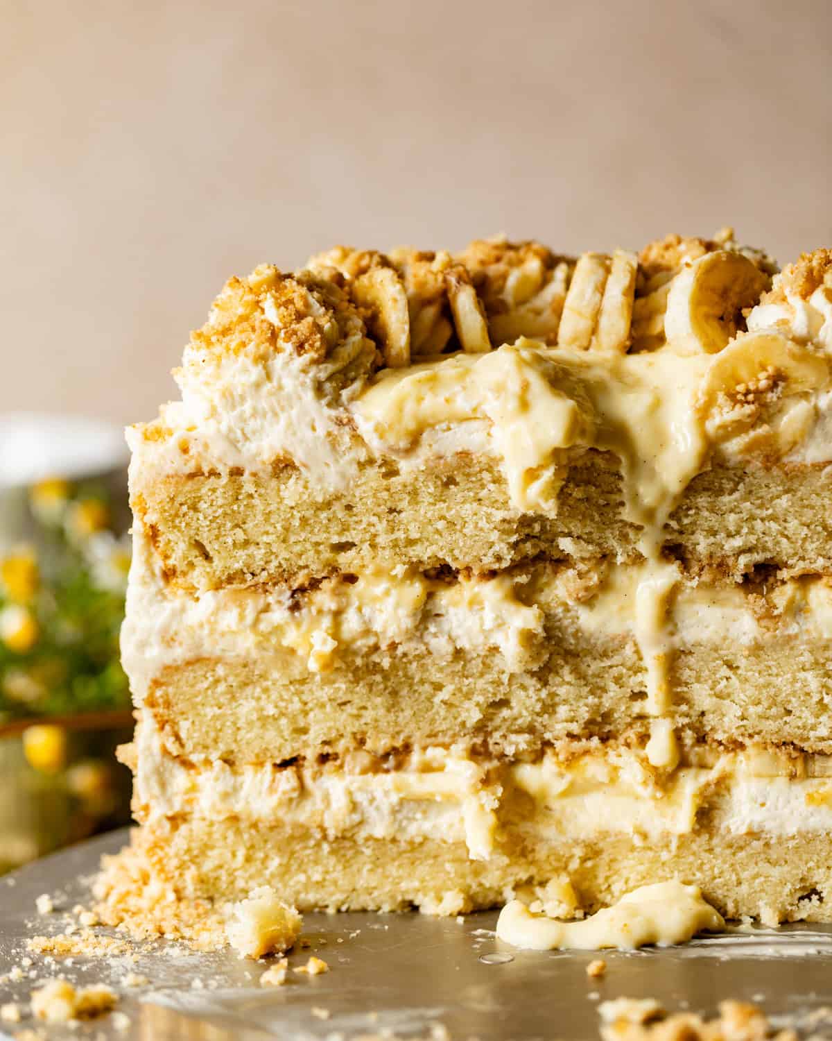 banana pudding cake on a cake stand with the cake cut open to see the inside layers.