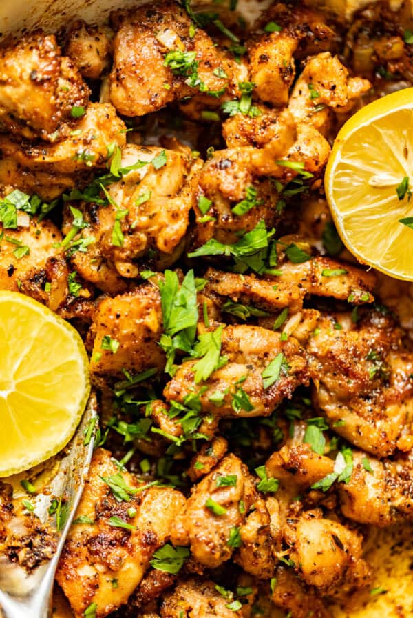 garlic butter chicken bites in a skillet with fresh sliced lemon and garnish with parsley.