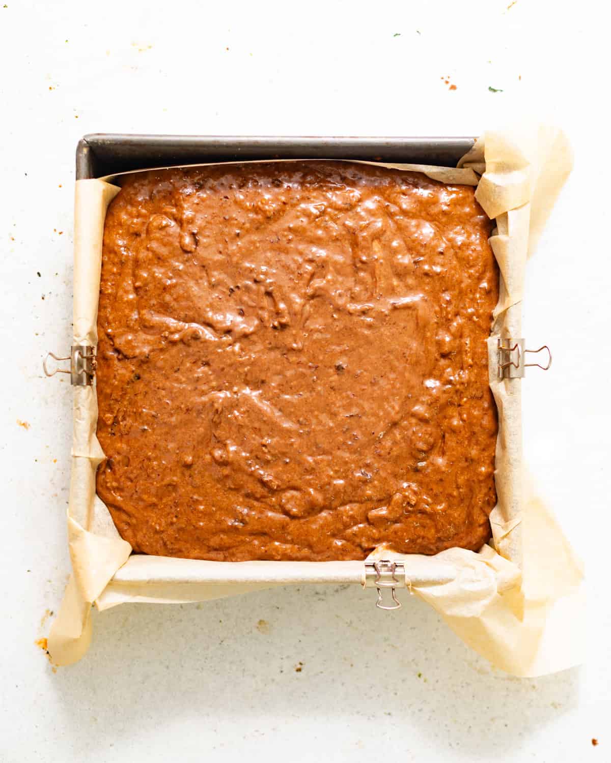 cake batter in a parchment paper lined square baking pan.
