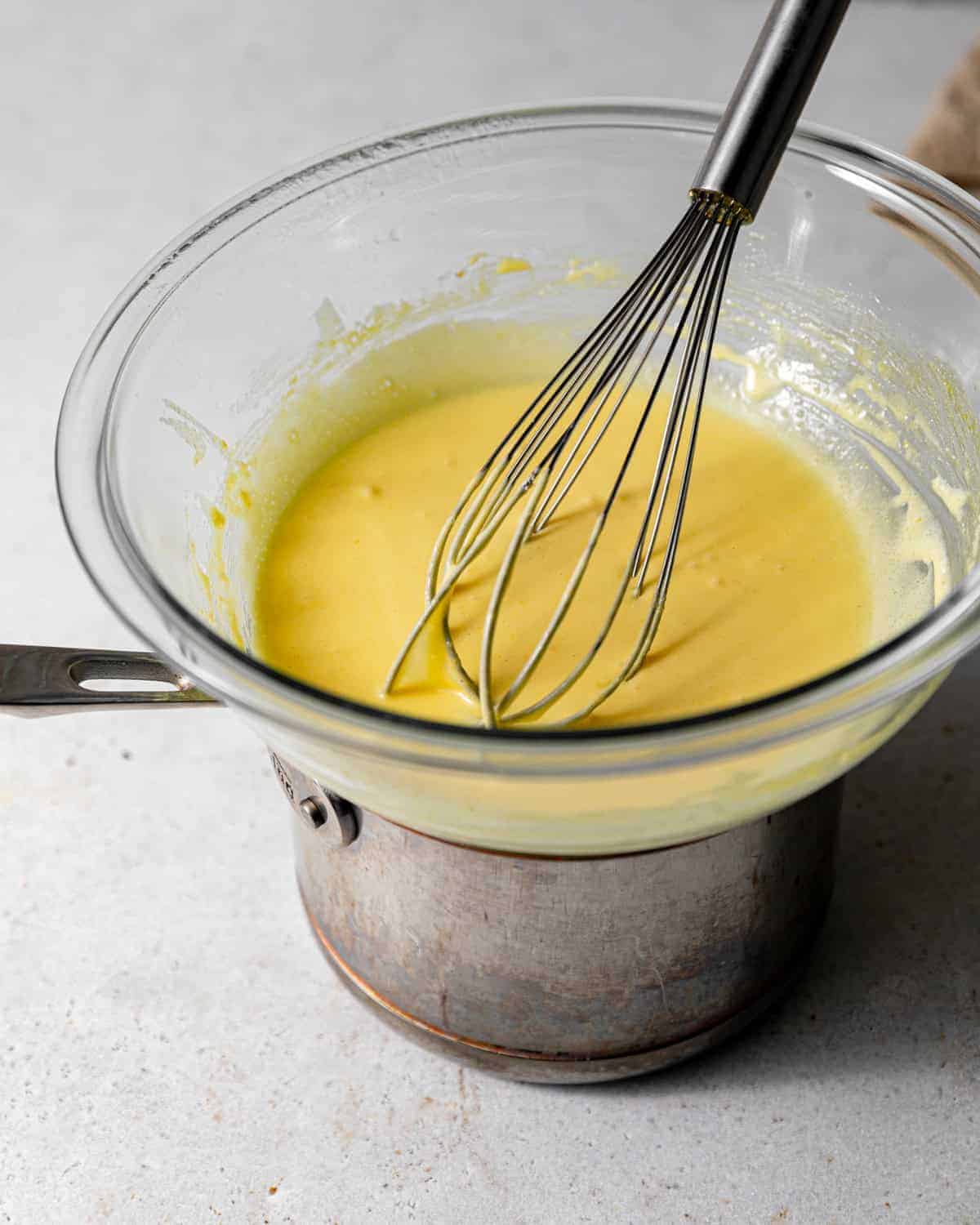 lemon curd on a double boiler with a whisk.