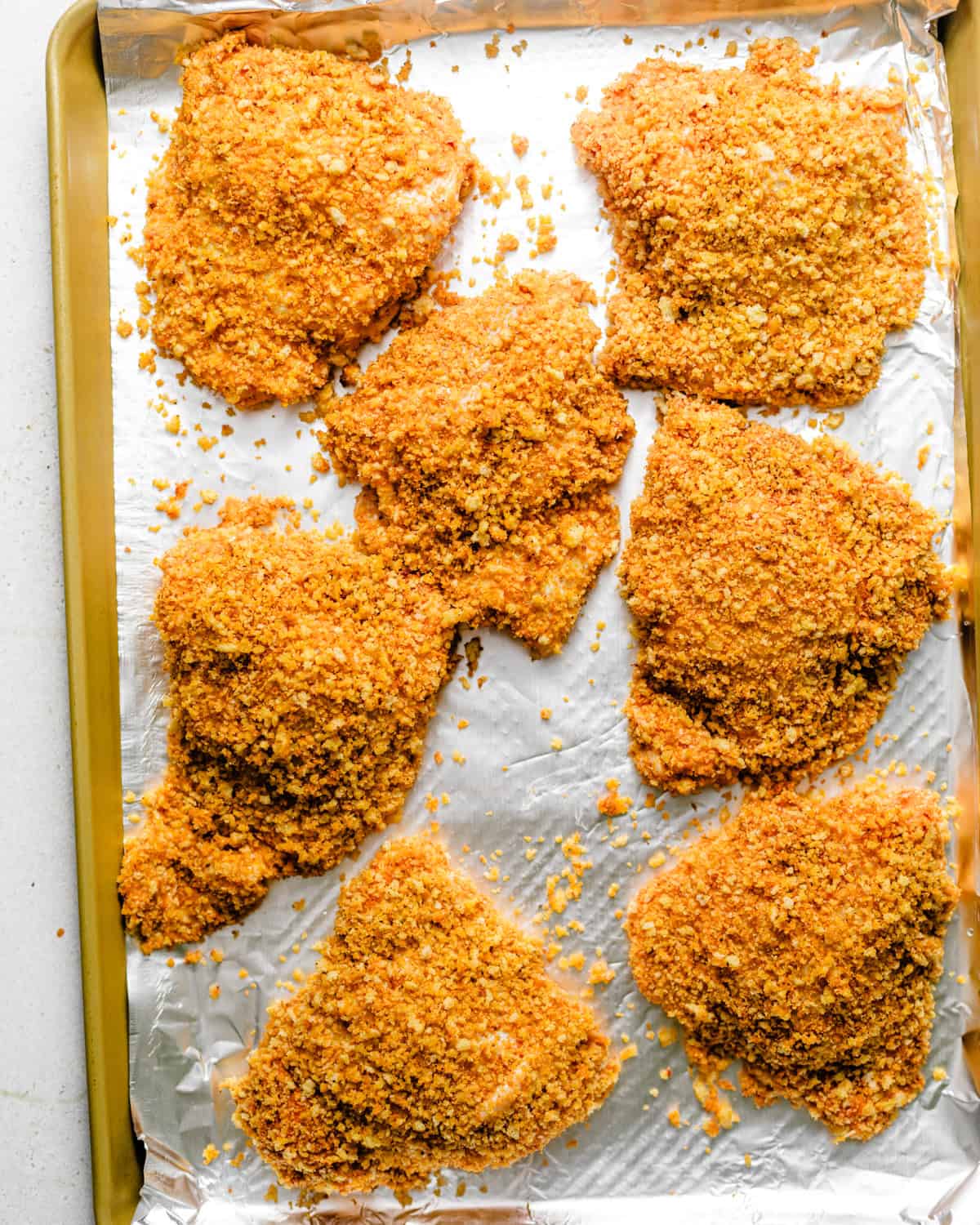 chicken coated in panko breadcrumbs and placed onto a wire rack on a foil lined rimmed baking sheet.
