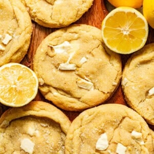 lemon white chocolate cookies on a board with sliced lemons.