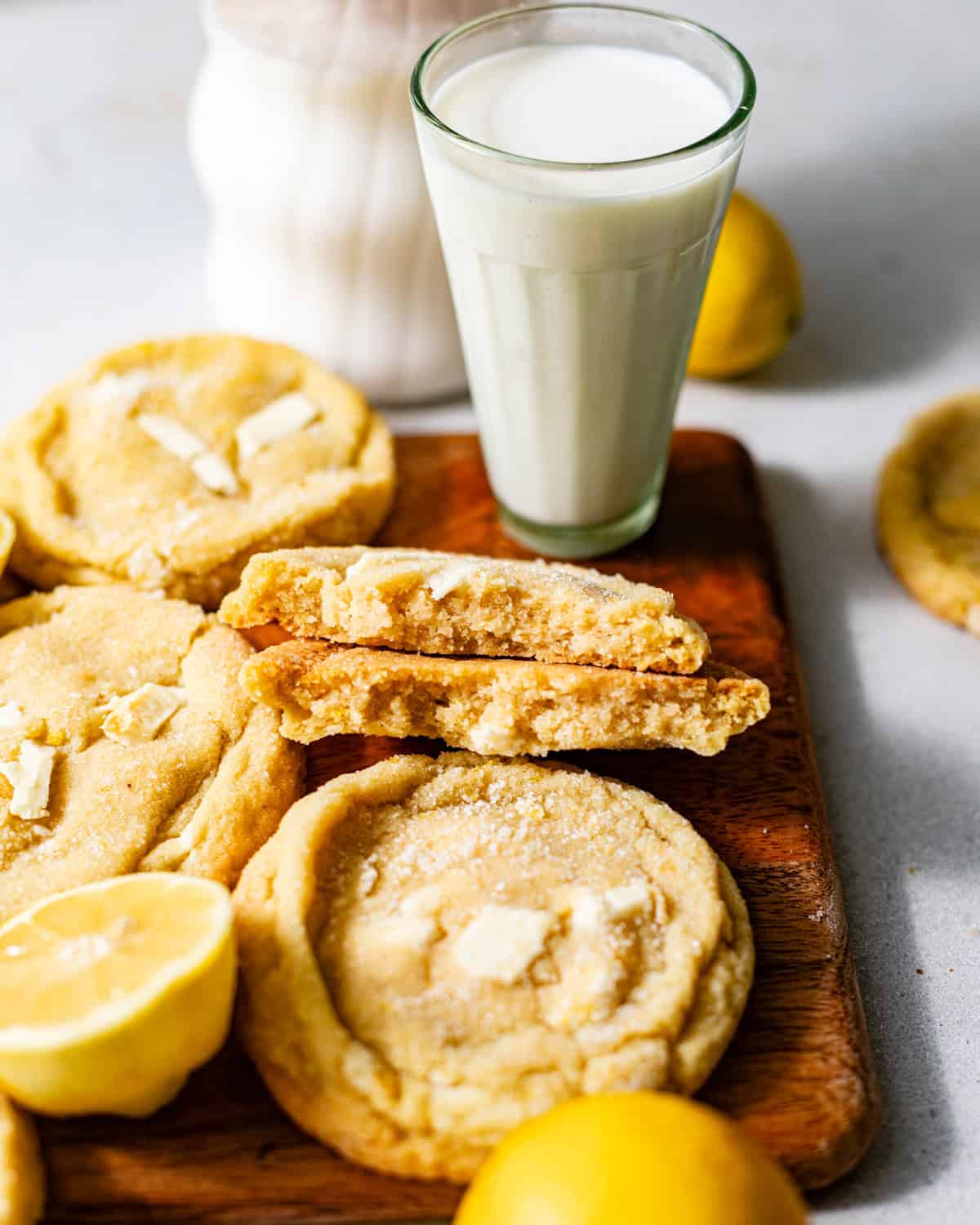lemon white chocolate cookies on a board with a glass of milk.