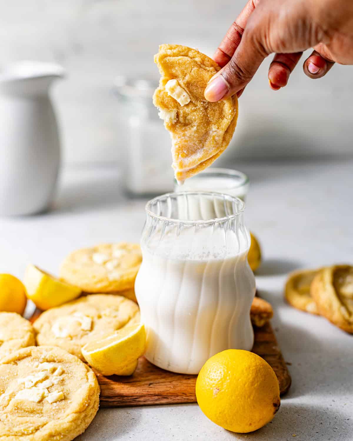 a hand dunking a cookie into a glass of milk.