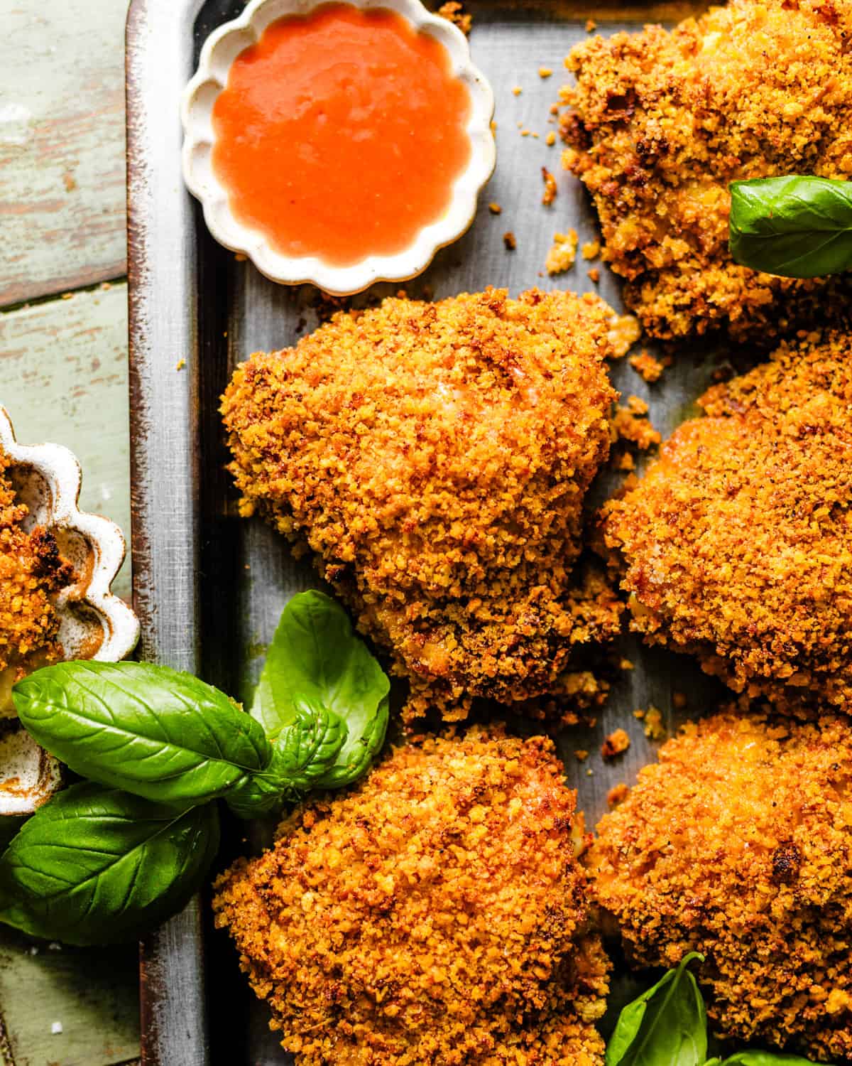 crispy oven fried chicken on a serving tray with a small bowl of hot sauce.