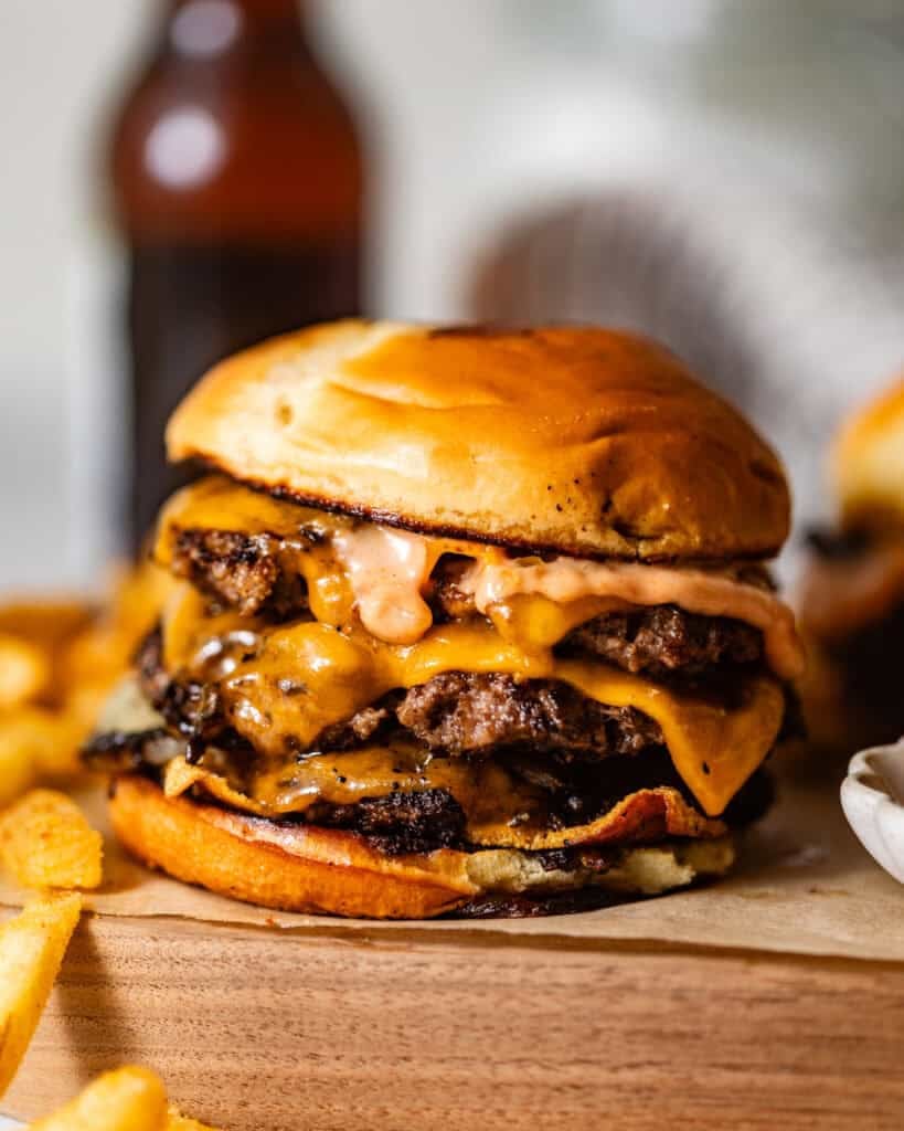 smash burger on a wooden board topped with fried onions, melted cheese, and burger sauce.