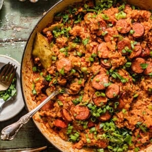 cajun sausage and rice in a skillet topped with chopped green onions.