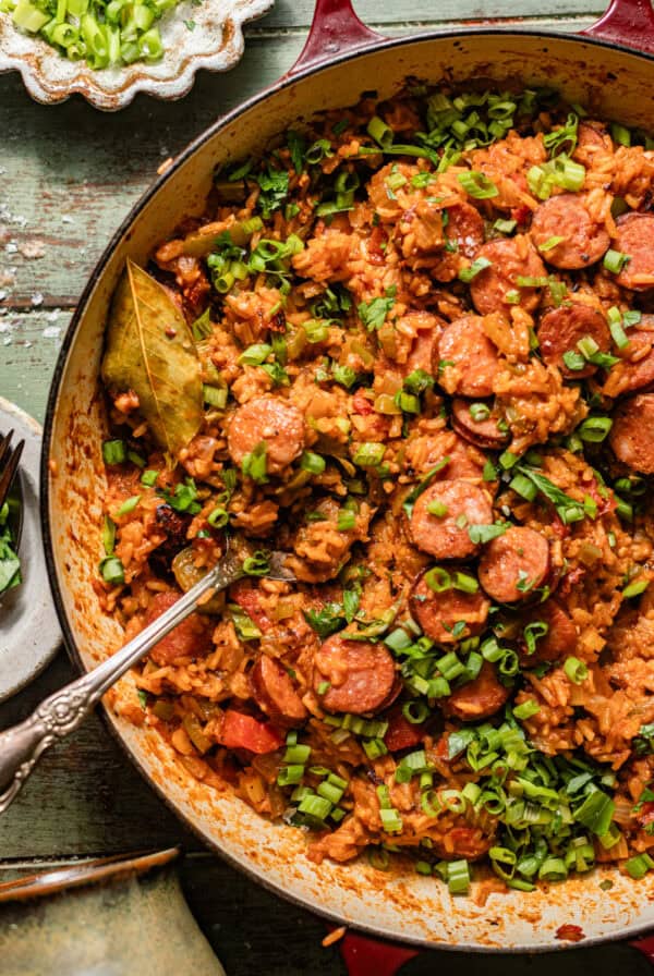 cajun sausage and rice in a skillet topped with chopped green onions.