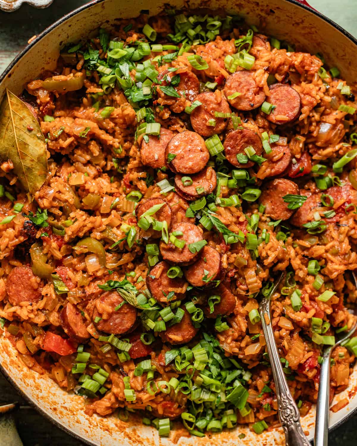 cajun sausage and rice in a skillet topped with chopped green onions.