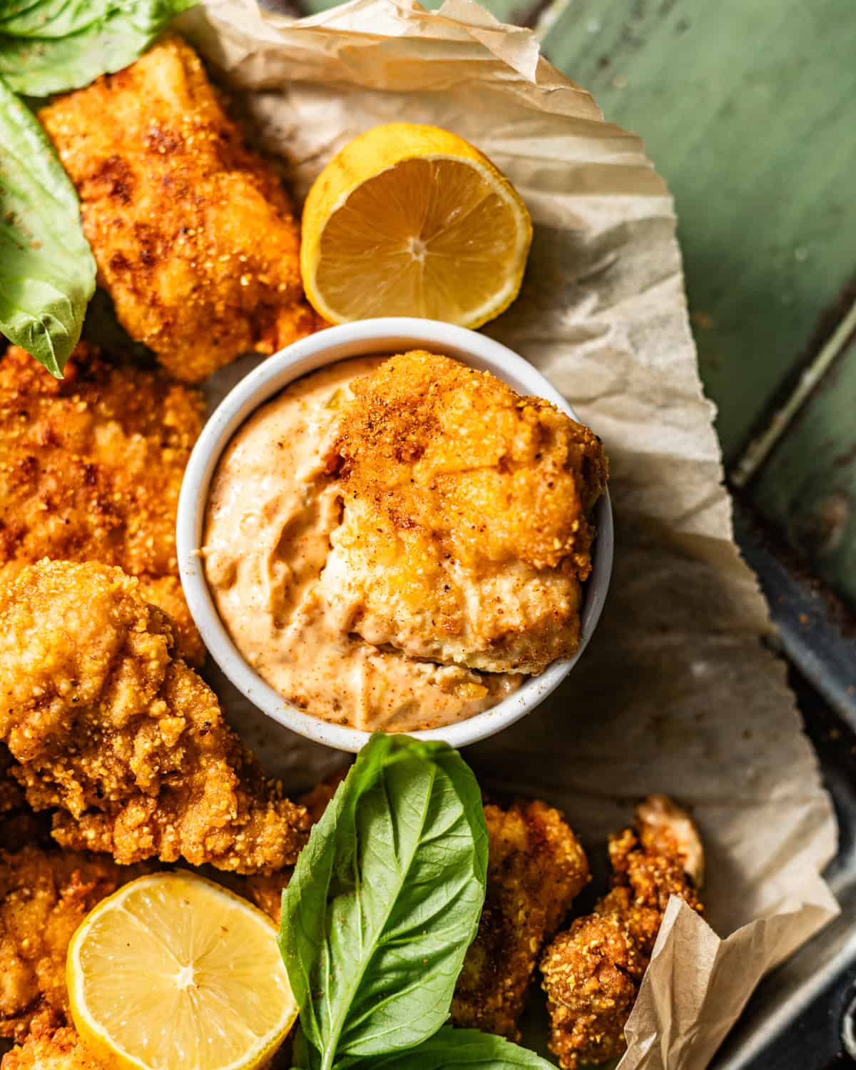 a catfish nuggets being dipped into a bowl of Cajun tartar sauce.